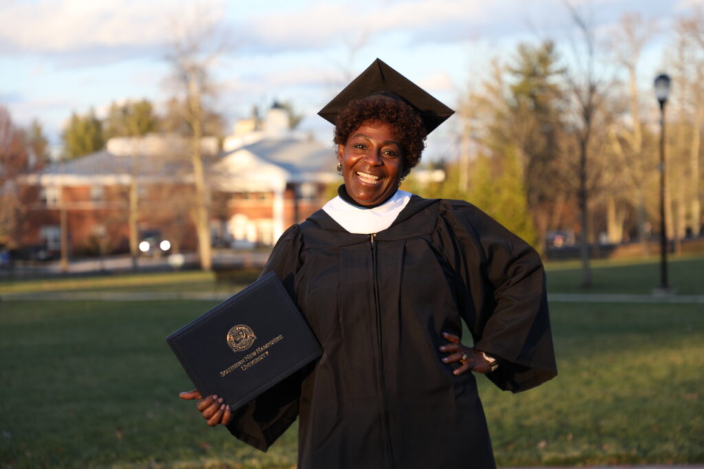 女人微笑的校园绿地,穿毕业帽和礼服,手里拿着文凭