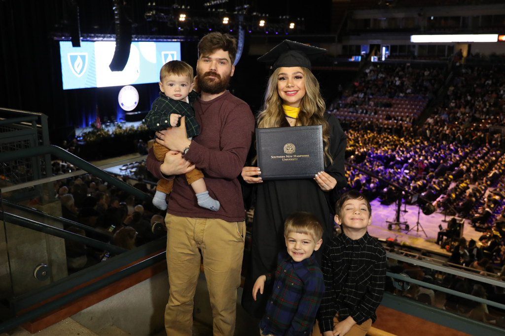 Tiare色度,伴随着她的三个男孩和爱的丈夫,在SNHU毕业典礼庆祝她的成就。